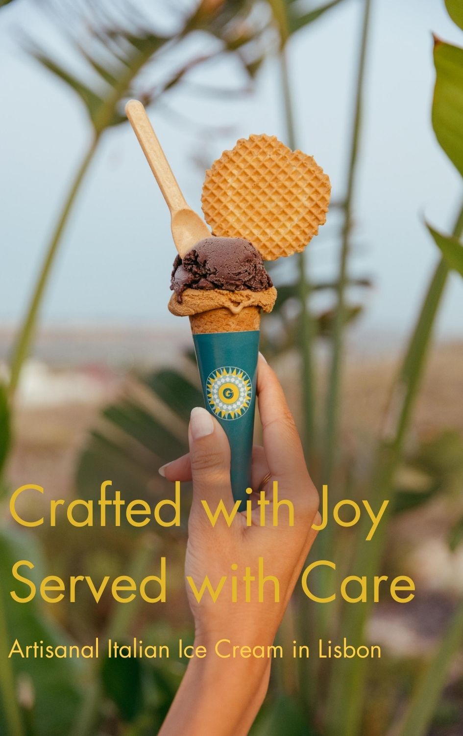 Hand holding a Giola cone with two scoops, spoon and waffle biscuit outdoors